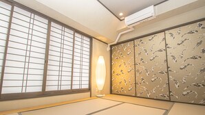Una habitación japonesa tradicional con suelo de tatami, paneles shoji y una puerta corredera con un motivo inspirado en la naturaleza.