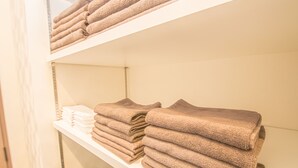 Una habitación de hotel con un estante ordenado que contiene toallas dobladas.