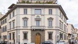 Un bâtiment historique doté d’une entrée centrale, de nombreuses fenêtres et d’un balcon.