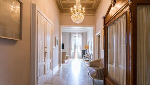 Un couloir orné d’un lustre, d’un grand miroir et d’une armoire en bois.