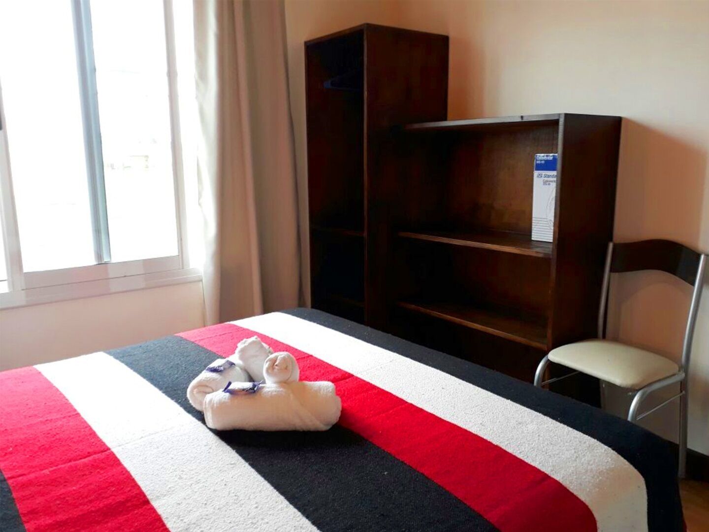 Ein Hotelzimmer mit einem Bett, einem Holzschrank und einem Sessel.