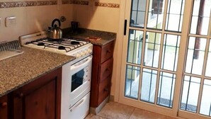 A kitchen with a gas stove, microwave, and wooden cabinets.