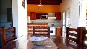 A kitchen with a brick wall, wooden cabinets, a microwave, and a stove.