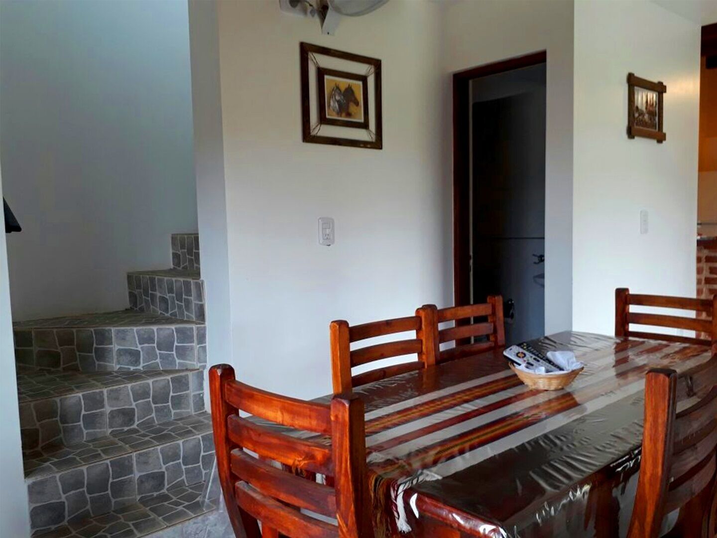 Un espace repas avec une longue table, des chaises en bois et un escalier en pierre.