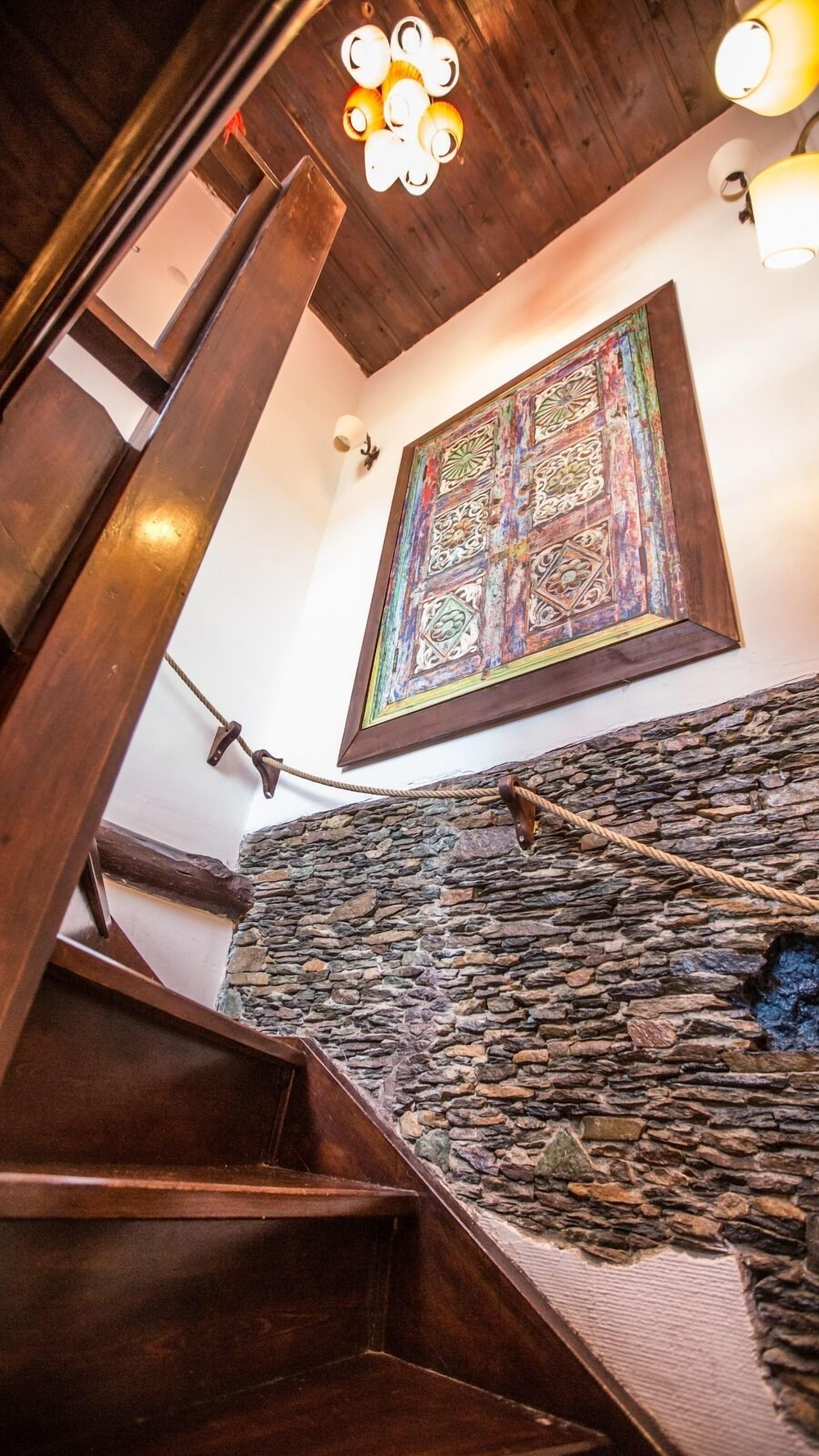Un escalier en bois avec un mur de pierre en bas.