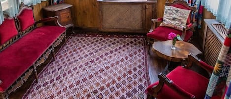 A cozy room with wooden beams, a patterned rug, and red furniture.