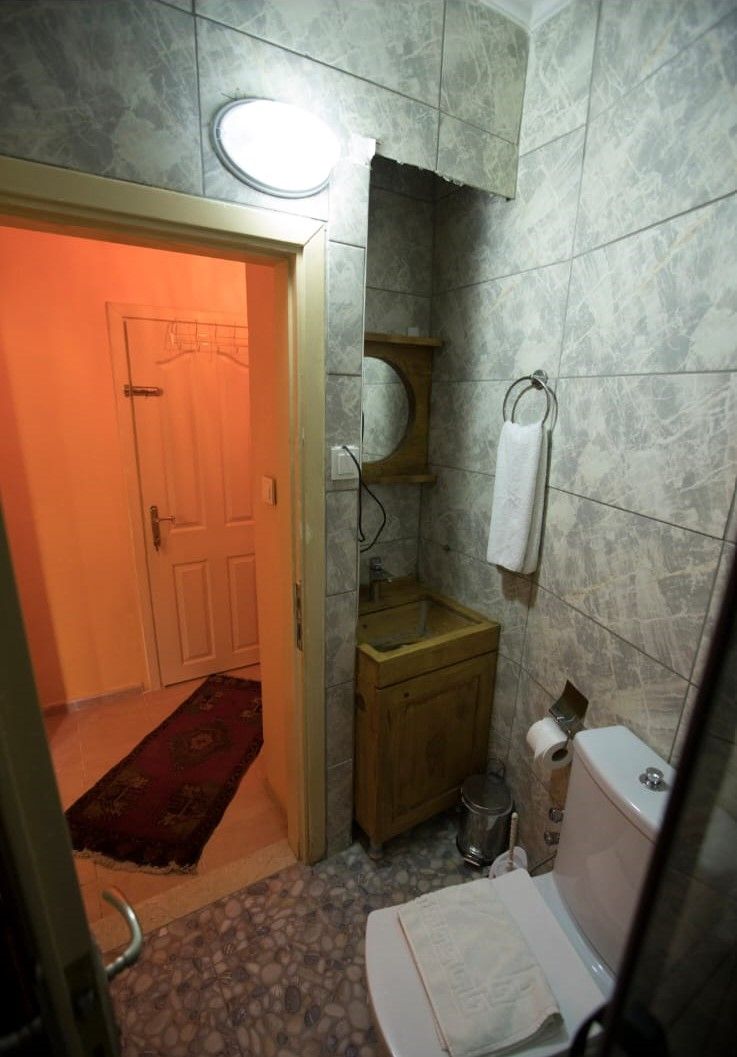 A small bathroom with a wooden cabinet, a towel hanging on the wall, and a tiled floor.