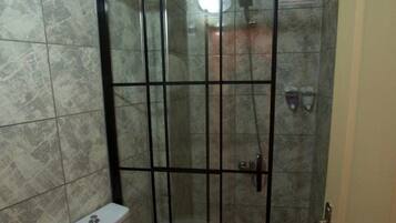 Un baño con ducha envuelta en vidrio, inodoro y lavabo.
