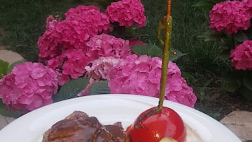 Un plato de comida con bistec, papas y una cereza sobre un plato blanco.