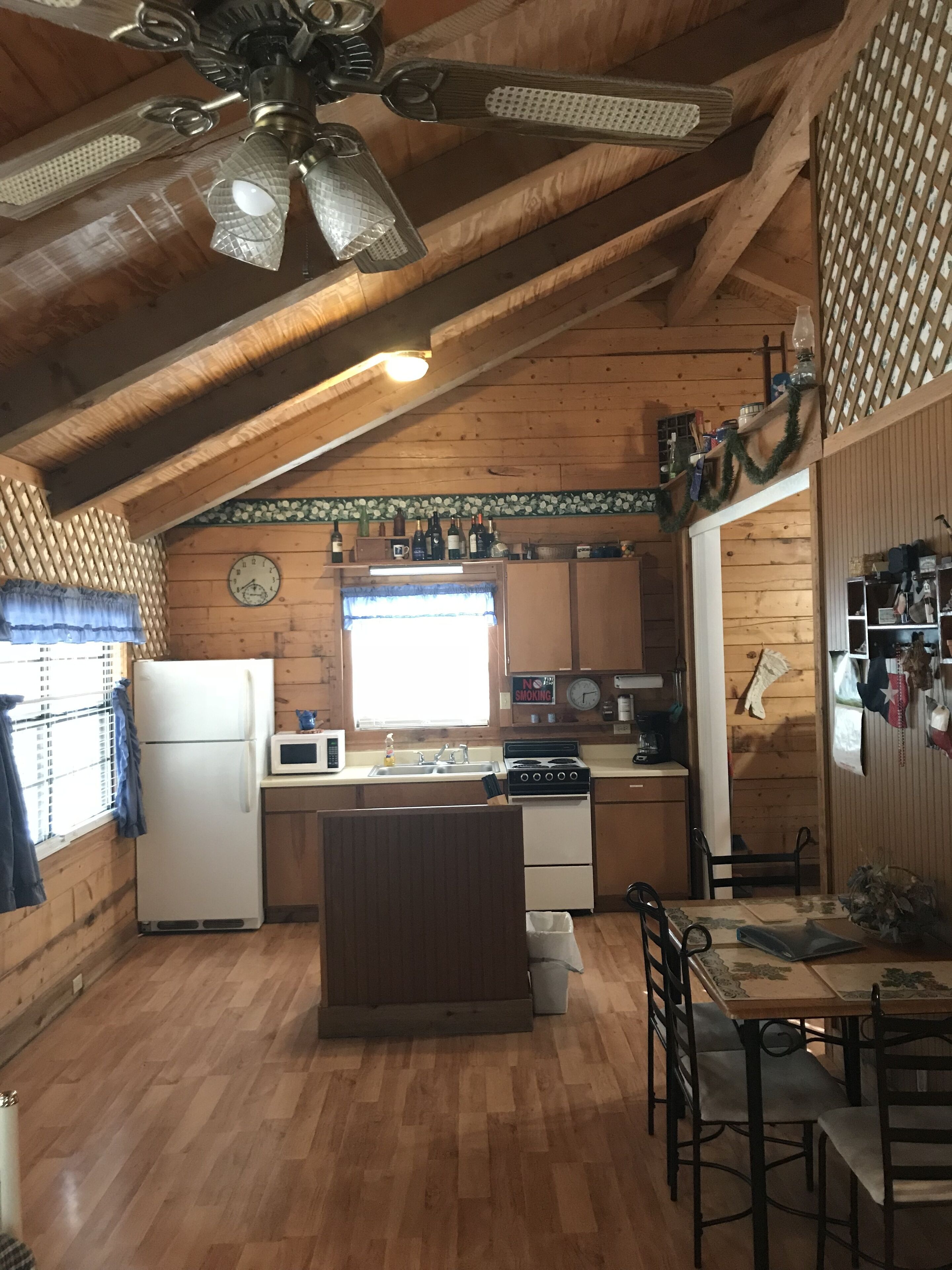 A rustic kitchen with wooden beams, a central island, a refrigerator, stove, and a microwave.