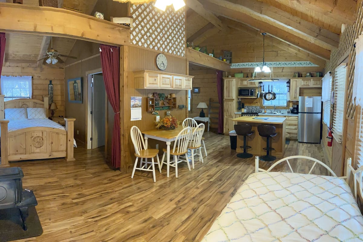 A cozy cabin with a wooden interior, a bed, a dining area, and a kitchen.
