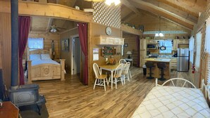 Un chalet confortable avec un intérieur en bois, un lit, un coin repas et une cuisine.