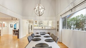 Une salle à manger spacieuse avec une longue table, de nombreuses chaises et un lustre central.