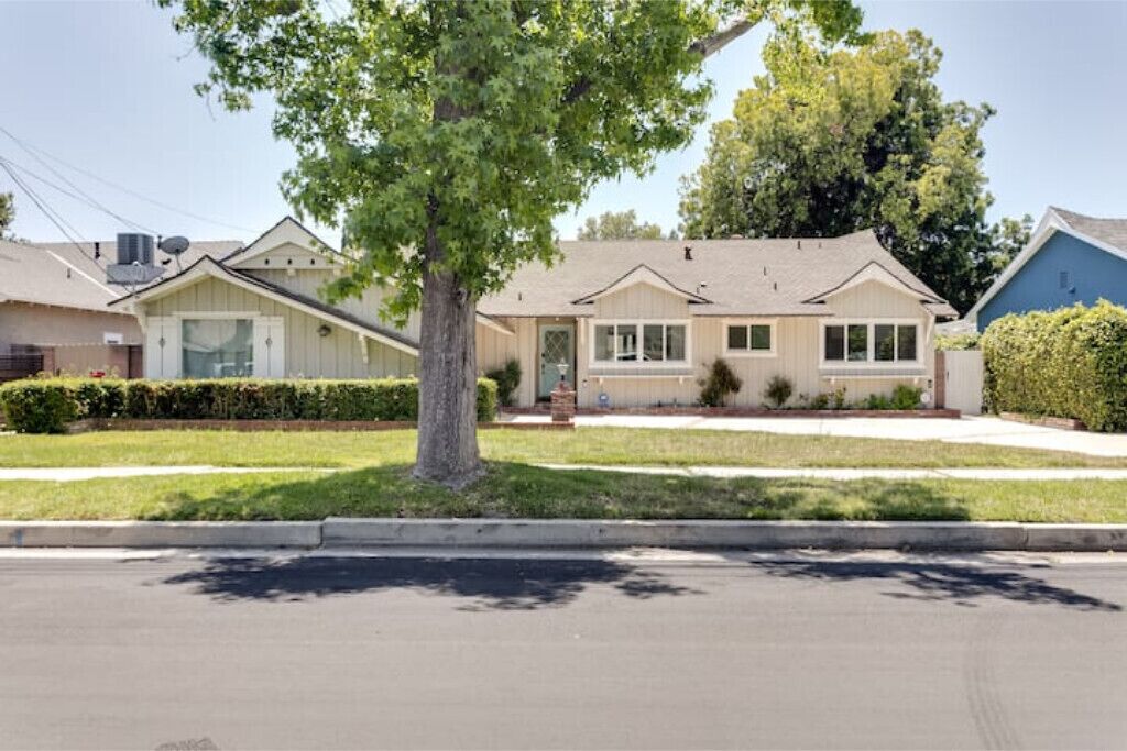 A single-story house with a front yard, a driveway, and a tree.