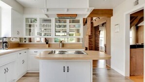 Une cuisine moderne avec des meubles blancs, un îlot central et un mur d’accent en briques.