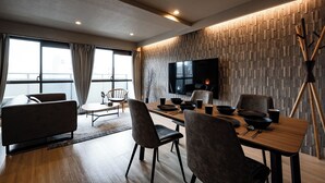 A modern dining area with a wooden table, chairs, and a flat-screen TV mounted on the wall. - Crice Hotel Namba II (Osaka)