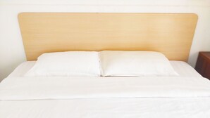 A bed with a wooden headboard and white bedding. - Rujia Hotel (Sihanoukville)