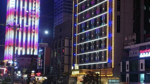 A multi-story building with illuminated vertical lines and a sign indicating a business or hotel. - Rujia Hotel (Sihanoukville)