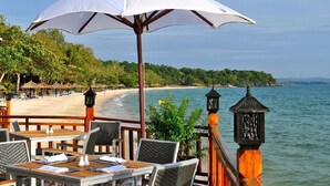 A beachside restaurant with outdoor seating, overlooking a sandy beach and the sea. - Rujia Hotel (Sihanoukville)