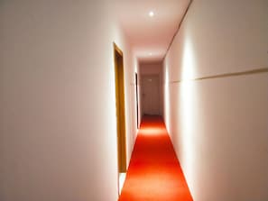 Enter a sleek hallway with a red carpet leading to a door.