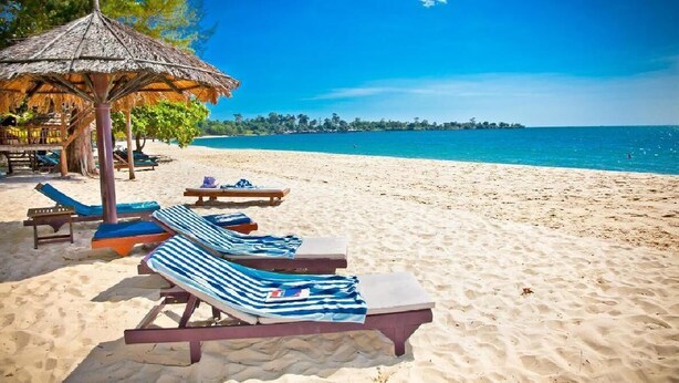 A beach with lounge chairs and a thatched umbrella. - Rujia Hotel (Sihanoukville)