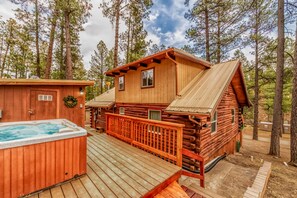 A log cabin with a hot tub, deck, and a view of the surrounding forest. - Rustic Grizzly Pet Friendly | Your Cozy Ruidoso Escape w/ Hot Tub & Bear-Themed Charm (Ruidoso)