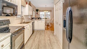 A modern kitchen with white cabinetry, stainless steel appliances, and a central island. - Fantastic location!!  Short walk to BEACH, Pools, and WATER PARK!  (Myrtle Beach)