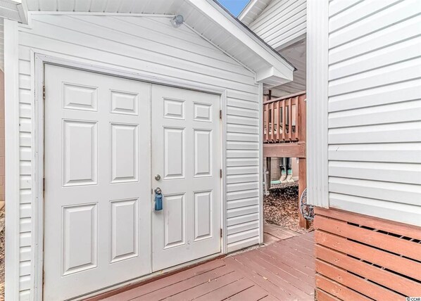 A white garage with a blue handle, a wooden deck, and a wooden fence.