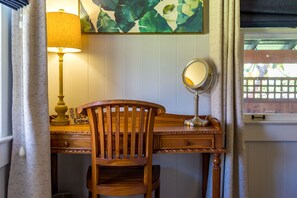 Un bureau en bois, agrémenté d’un miroir, d’une lampe et d’une œuvre d’art encadrée accrochée au mur.