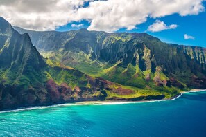 Un paysage montagneux côtier offrant une vue dégagée sur l’océan et une plage.