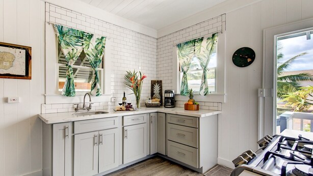 A modern kitchen with white cabinetry, a wooden countertop, and a gas stove. - Waimea Beach Cottage by Destination Kauai - Charming 2BD, A/C, Walk to Ocean/Pier (Waimea)