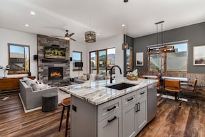 Enjoy cooking in this well-equipped kitchen with a large island, sink, and stone fireplace.