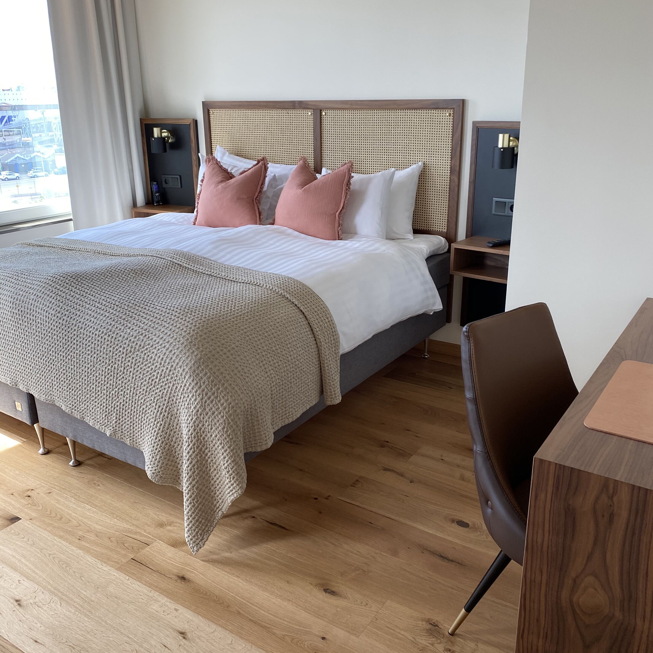 Una camera da letto moderna con un letto grande, una testiera in legno e un comodino con una lampada.