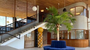 A modern lobby with a staircase, a central palm tree, and a blue seating area. - Fritiden Hotell & Kongress (Ystad)