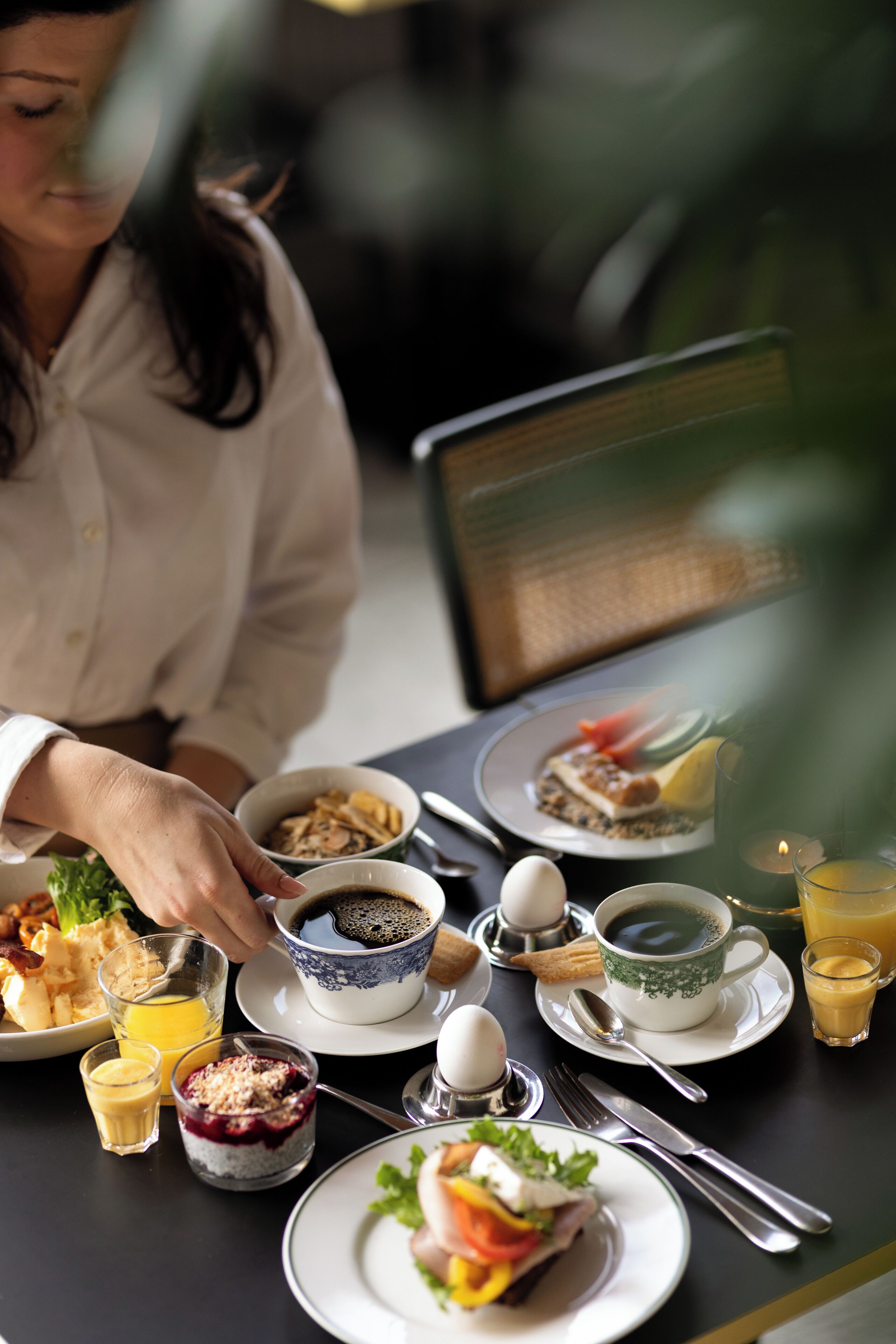 A breakfast setting with various dishes, including eggs, toast, and fruit, on a table.