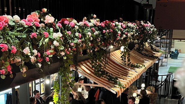 A restaurant with a high ceiling, hanging floral decorations, and a dining area with tables and chairs. - Fritiden Hotell & Kongress (Ystad)