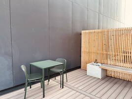 A modern outdoor seating area with a table and chairs, a wooden fence, and a bench.