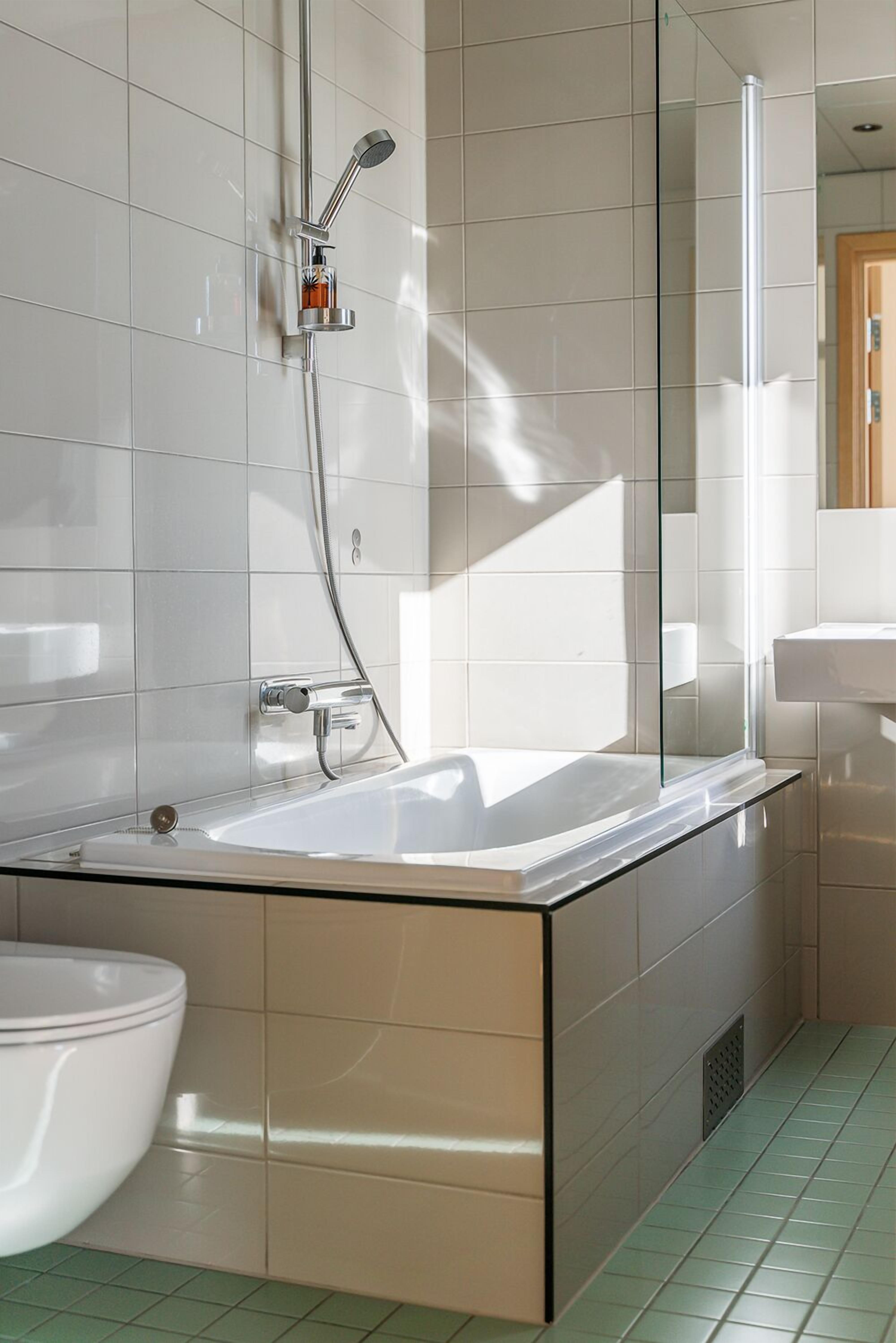 A modern bathroom with a glass-enclosed shower, a white bathtub, and a sink.
