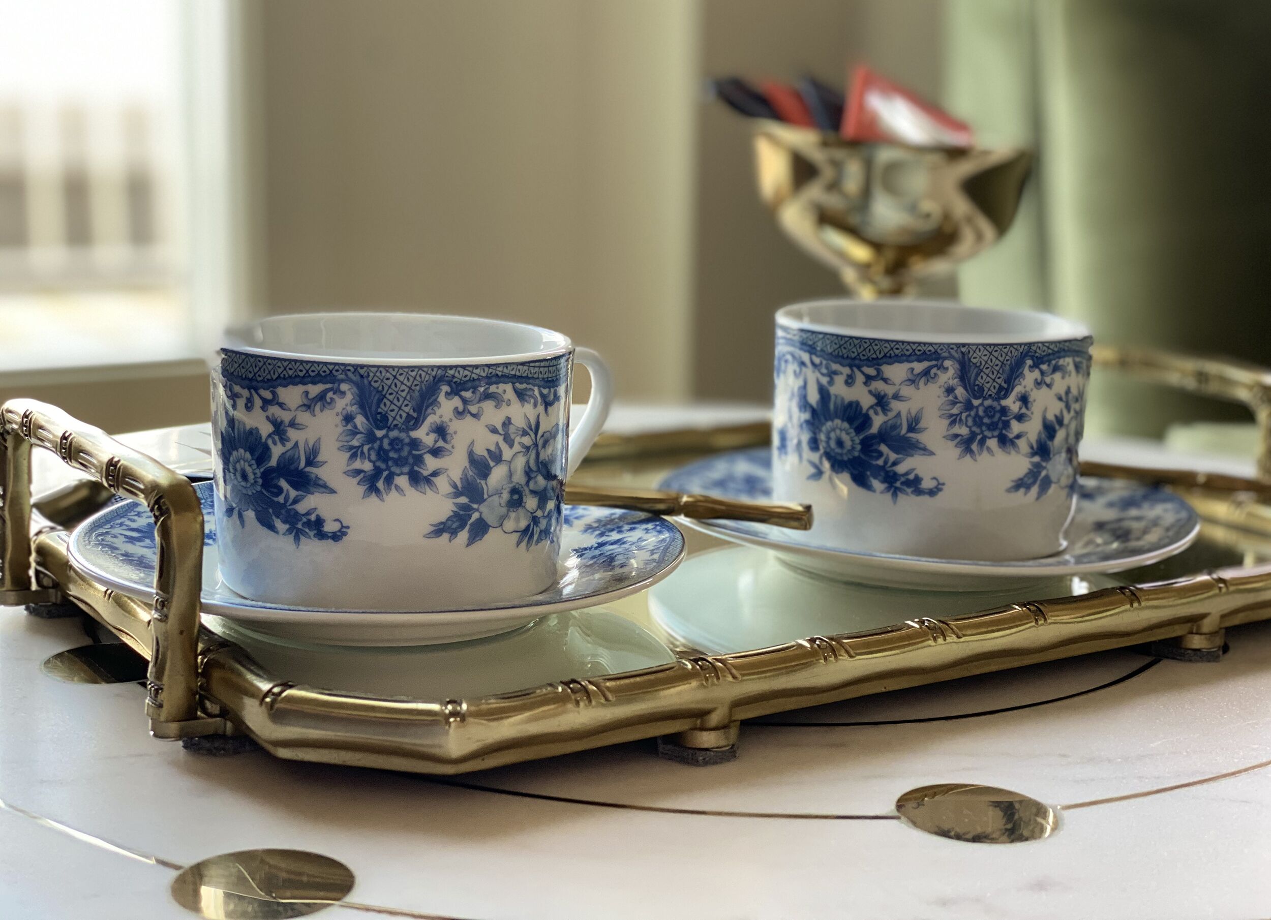 A tray with two cups and saucers, a spoon, and a decorative bowl on a table.