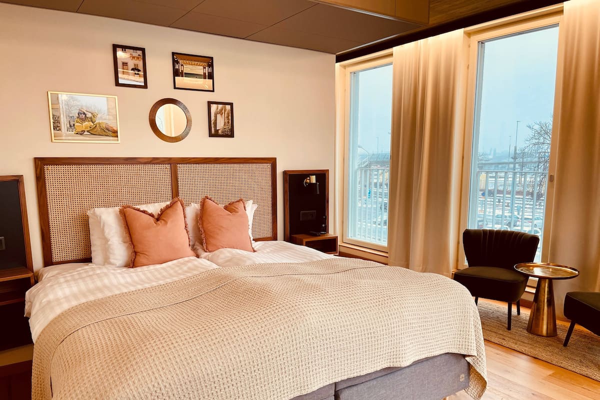 Hotelkamer met een groot bed, een televisie, een stoel en uitzicht op de stad.