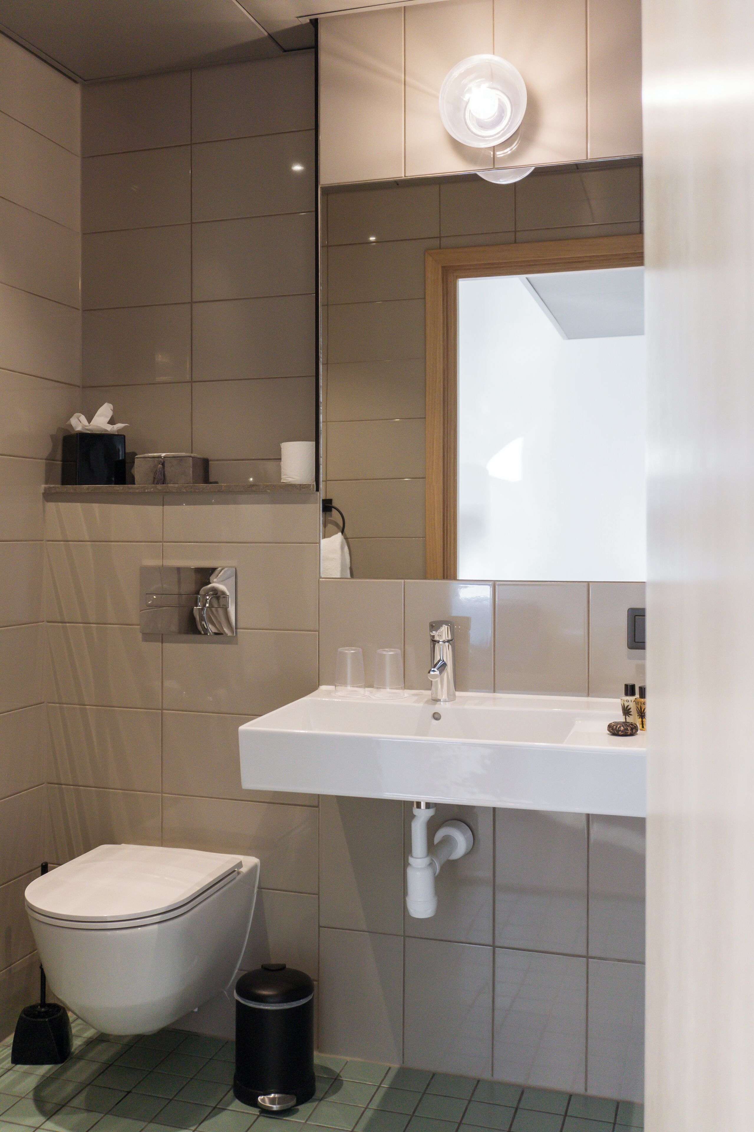 A modern bathroom with a toilet, sink, and mirror.