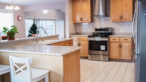 Una cocina moderna con armarios de madera, electrodomésticos de acero inoxidable y una isla grande con una silla blanca.