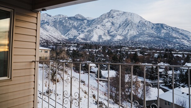 Un balcón con vistas a montañas nevadas y una zona residencial.