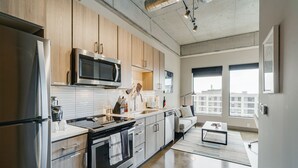 Una cocina moderna con electrodomésticos de acero inoxidable, armarios de madera y un amplio ventanal con vistas a la ciudad.