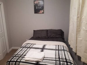 A bedroom with a bed, a pillow, a blanket, and a wall decoration.