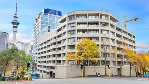 A multi-story hotel with a curved facade, a prominent 'AUT' sign, and a view of the nearby tower. - Chic Metro Apartment with Free Parking and Air-con (Auckland CBD)