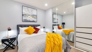 A modern bedroom with a large bed, a nightstand, a mirror, and a painting on the wall. - Chic Metro Apartment with Free Parking and Air-con (Auckland CBD)