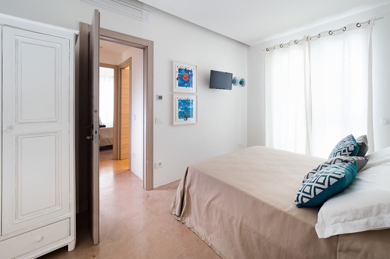 Une chambre à coucher avec un lit, une télévision et des œuvres d’art accrochées au mur.