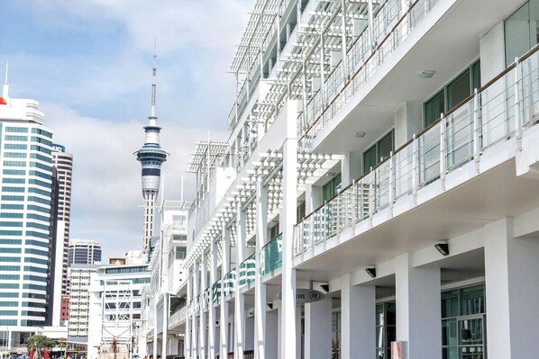 A modern hotel with multiple floors, large windows, and a prominent tower in the background.