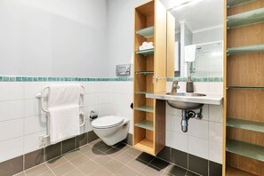 A modern bathroom with a toilet, a sink, and a mirror. There are shelves above the sink and a towel rack on the wall.